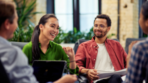 Young cheerful business woman discussing project results with colleagues while working together in the modern office.